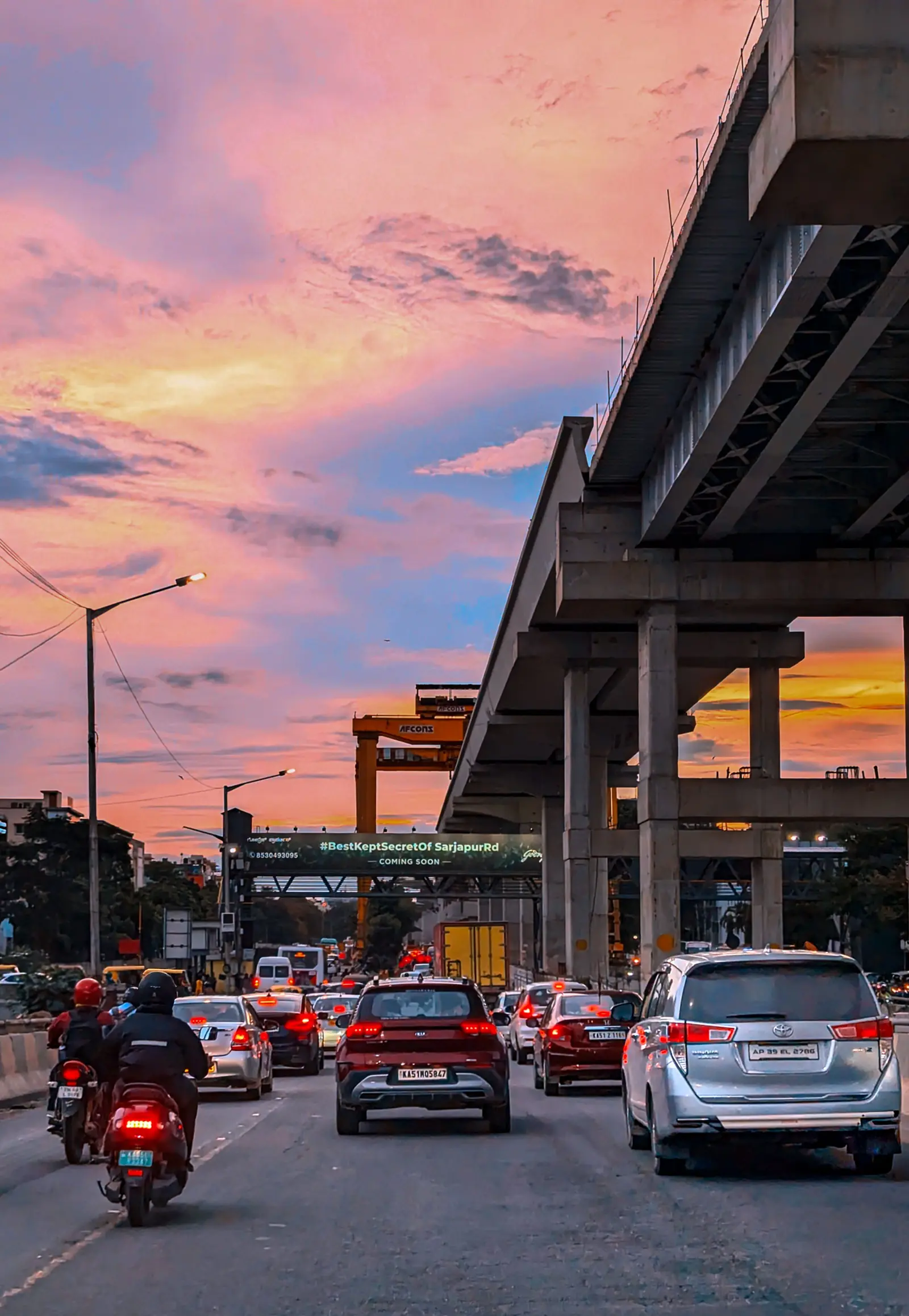 Evening traffic on Sarjapur Road under the metro line being built, at sunset